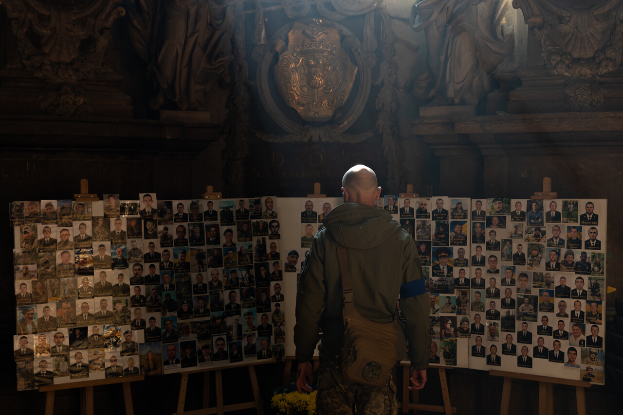 3월17일, 우크라이나 르비우의 ‘가장 거룩한 사도 베드로와 바울교회’에서 열린 장례미사에 참여한 한 군인이 사망한 우크라이나 군인들의 사진이 걸린 성당 벽을 바라보고 있다. ⓒ 장진영