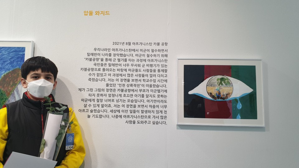 지난 2월 '세계시민포럼 그림대회'에서 입상한 바라카 작은 도서관 아이가 서울 여의도 국회의원 회관에 전시된 자신의 출품작 옆에 서있다. ⓒ 바라카작은도서관