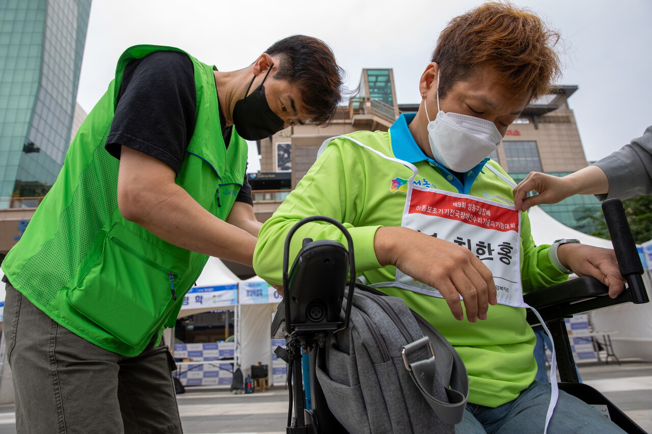 성동장애인종합복지관 자원봉사자가 전동부문 참가자 최한홍(39) 씨의 배번 착용을 돕고 있다. 박시몬 기자