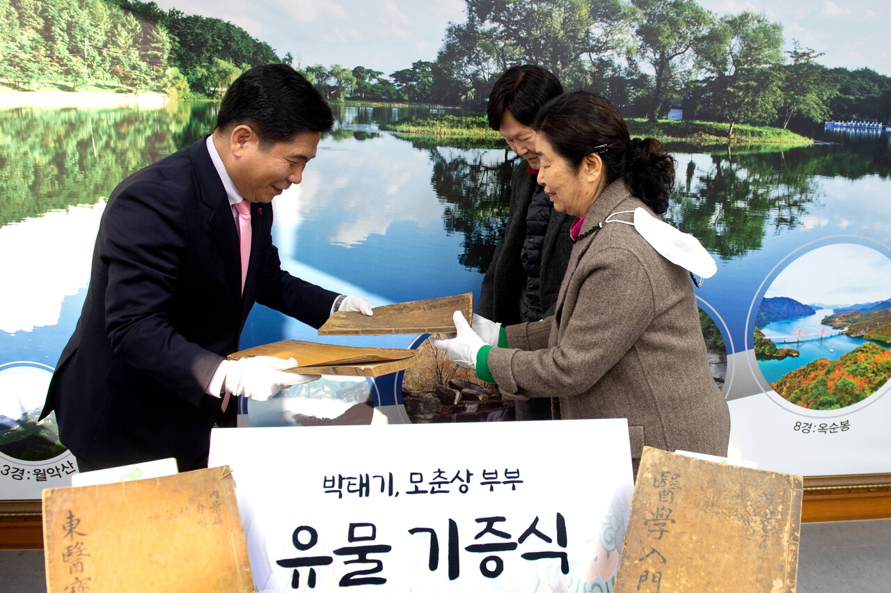 지난해 12월 22일 제천시청에서 열린 유물 기증식에서 박 씨 부부가 김창규 시장에게 고서를 전달하고 있다. 제천시청 제공