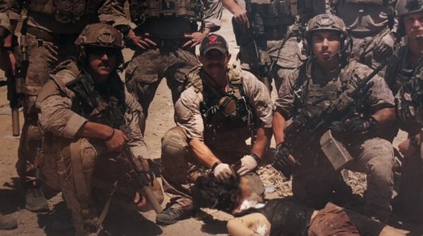 에디 갤러거(가운데)가 죽은 ISIS 포로의 머리를 잡고 있다. 출처: 더라인, 애플티비.