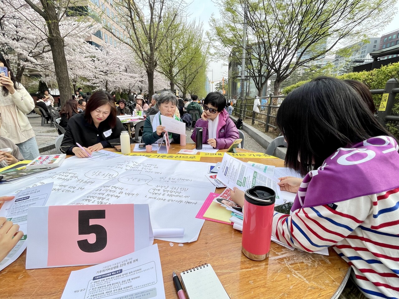 사라 여성환경연대 활동가가 진행을 맡은 5모둠의 참가자들이 ‘기후위기비상행동 22대 국회 과제’ 자료를 보며 토론하고 있다. 전예나 기자