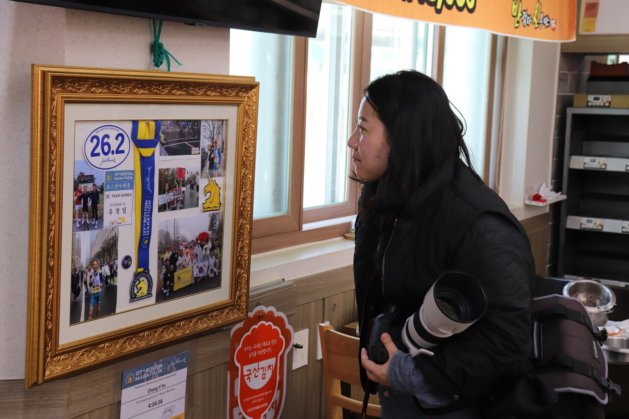 지난해 11월 22일, 해남군에 있는 어느 식당의 벽면에 걸린 사진을 조 기자가 바라보고 있다. 이 사진을 통해, 식당 사장이 각종 달리기대회에 자주 출전한다는 걸 알게 된 조 기자는 즉석에서 그 사연을 취재했다. 최영범 기자