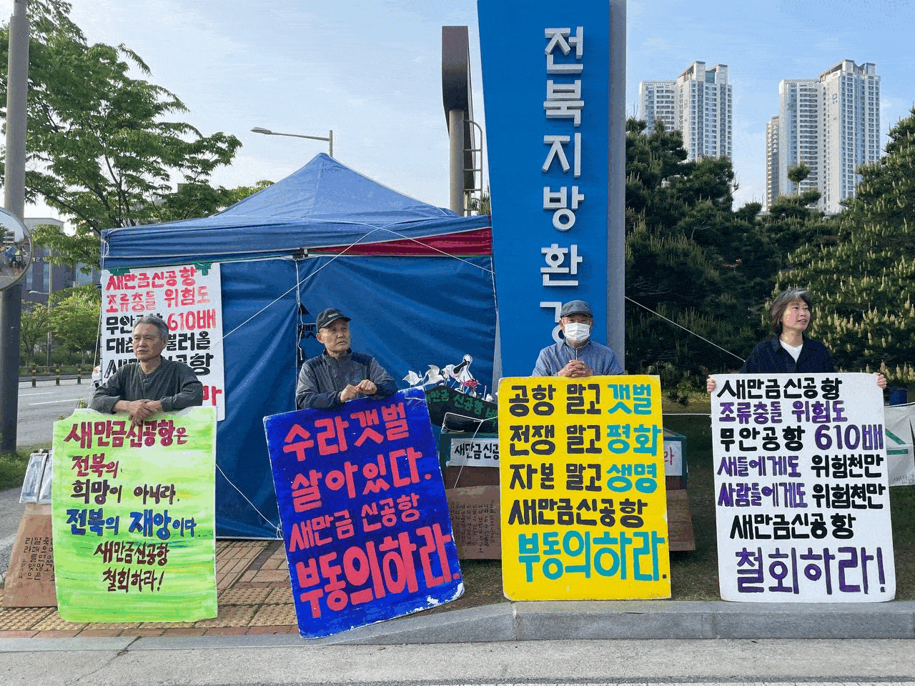 새만금신공항백지화공동행동 소속 활동가 등이 24일 전북지방환경청 앞에서 새만금신공항 부동의를 촉구하는 손팻말을 들고 시위하고 있다. 일부 참가자들은 풍물놀이로 사기를 북돋았다. 새만금신공항백지화공동행동 제공