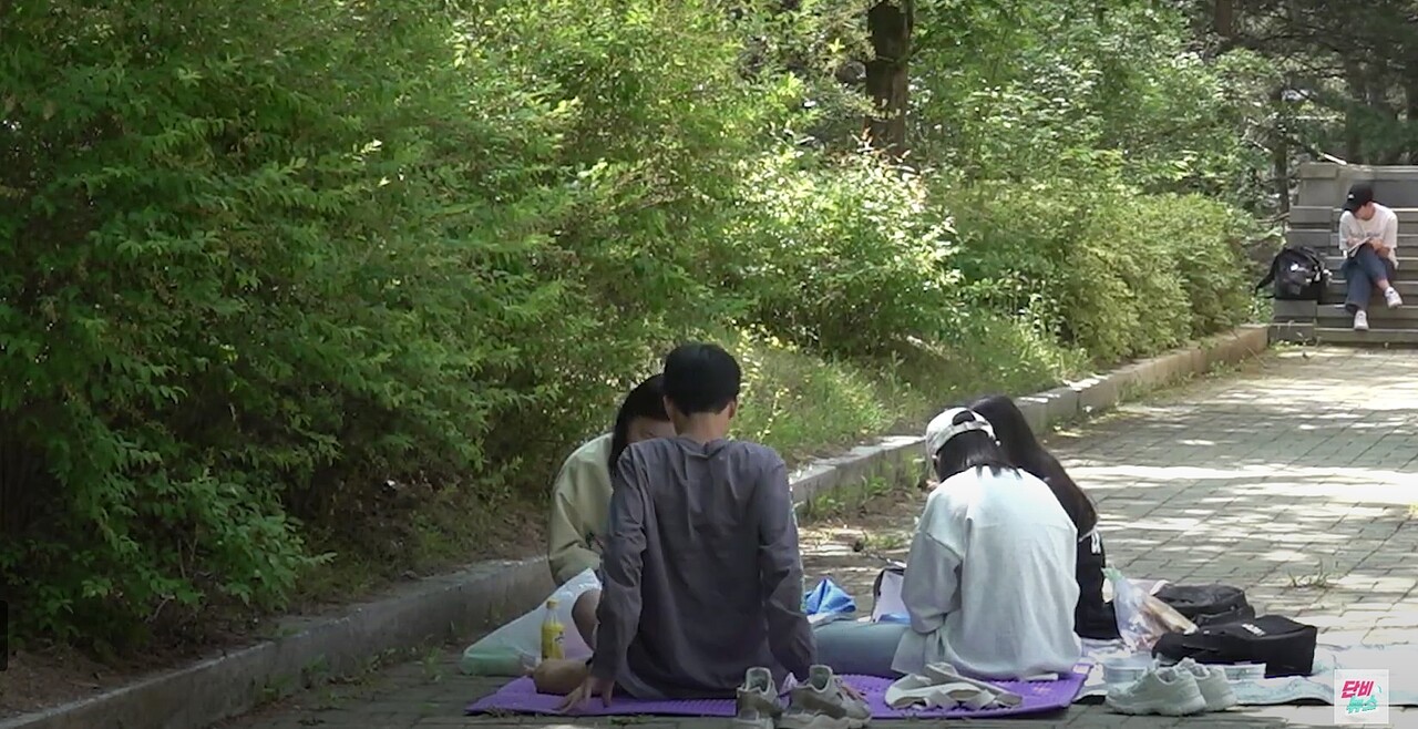 2024년 제6회 민송백일장 참가자가 세명대학교 캠퍼스에 앉아 글을 쓰고 있다. 단비뉴스 유튜브 갈무리