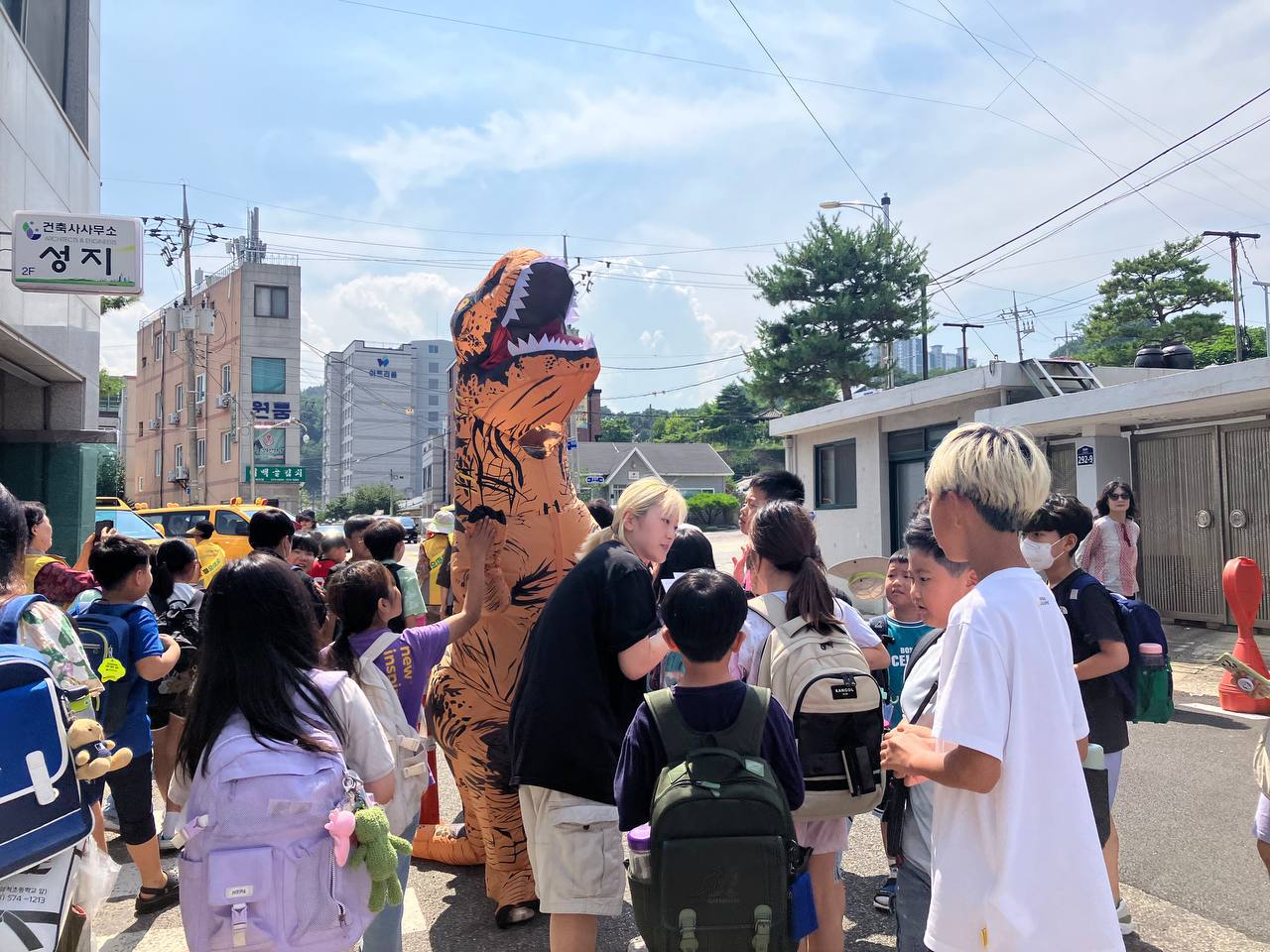 지난해 7월 삼척 이주를 위한 사전 합숙과정에서 수아 활동가와 청년기후긴급행동의 마스코트 ‘김공룡’ 복장의 회원 등이 삼척초등학교 앞에서 어린이들을 만나고 있다. 청년기후긴급행동 제공
