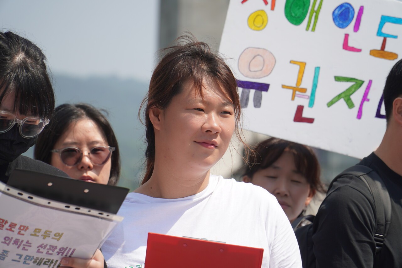 박연지(33) 씨가 지난 6월 2일 서울 광화문광장에서 열린 ‘발달장애인유권자 투표보조 권리 보장 촉구 기자회견’에서 피켓을 들고 서 있다. 최진주 PD